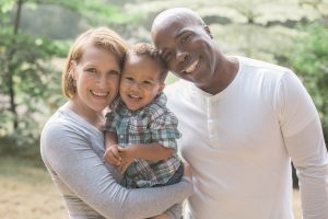 mother, father and a little daughter are smiling at the camera