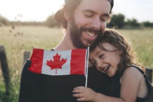 father and daughter holding Canadian flag