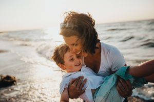 smiling mother holding son at the beach