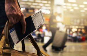 traveller in the airport holding a passport and a boarding pass inside