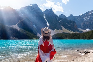 A woman holding a Canadian flag looking at a lake in Canada