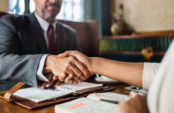 man and woman shaking hands above legal papers