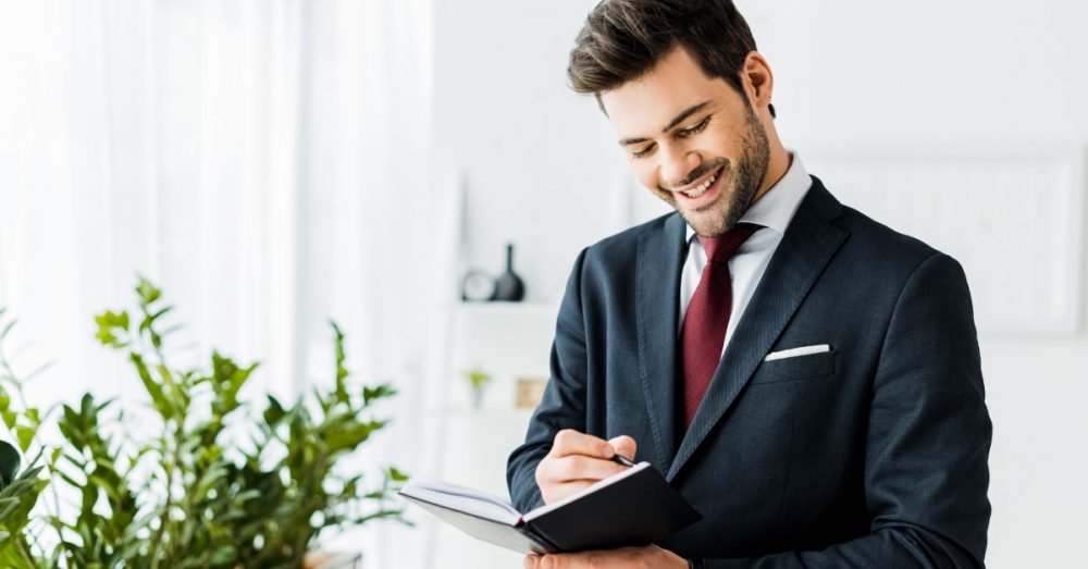 smiling young man writing in a notebook